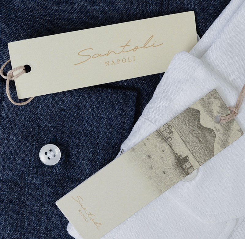 Close-up of Santoli Napoli clothing tags with a button on a fabric background